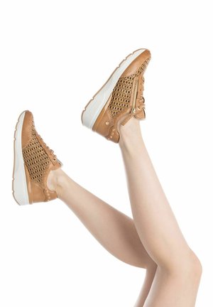 Zapatillas de cuero marrón con un upper texturizado de tejido trenzado, suela blanca y cremallera lateral. El diseño incluye tachuelas decorativas y cordones para un ajuste seguro.