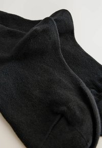 Chaussettes en coton noir avec une texture côtelée, dotées d'un design sans couture au niveau des orteils et d'un léger stretch pour plus de confort et d'ajustement.