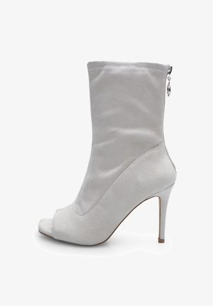 Sive čizme do gležnja od sueded materijala s otvorenim nožnim prstom, visokim štiklama, čistim linijama i bočnim patentnim zatvaračem. Mekana tekstura i glatka završnica.