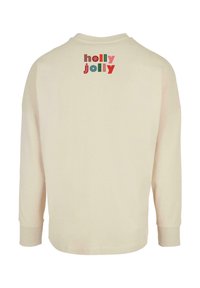 Ilgi piedurkņu krēmkrāsas kokvilnas tops ar daudzkrāsainu "holly jolly" grafiku uz augšējās aizmugures un ribotajiem jostiem. Gluda tekstūra.
