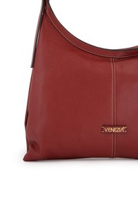 Red leather shoulder bag with a textured finish, featuring contrast stitching and a branded gold plaque. Curved design and wide opening.