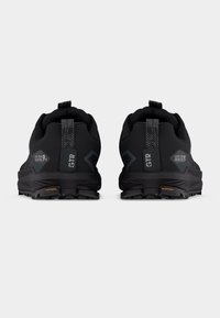 Ζεύγος μαύρων παπουτσιών ορεινού τρεξίματος με ανθεκτικές σόλες και θηλιές, με λογότυπο Gore-Tex Lone Peak 4+ στη φτέρνα.