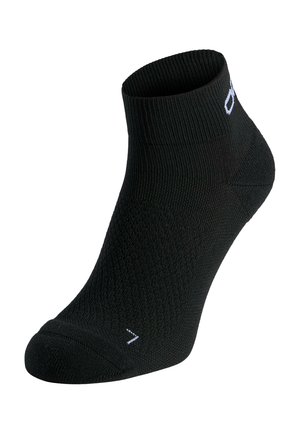 Schwarze Knöchelsocke mit geripptem Bündchen und strukturiertem Strickmuster, mit einem kleinen weißen Logo nahe der Oberseite und einem weißen Buchstaben "L" auf der Zehenpartie.