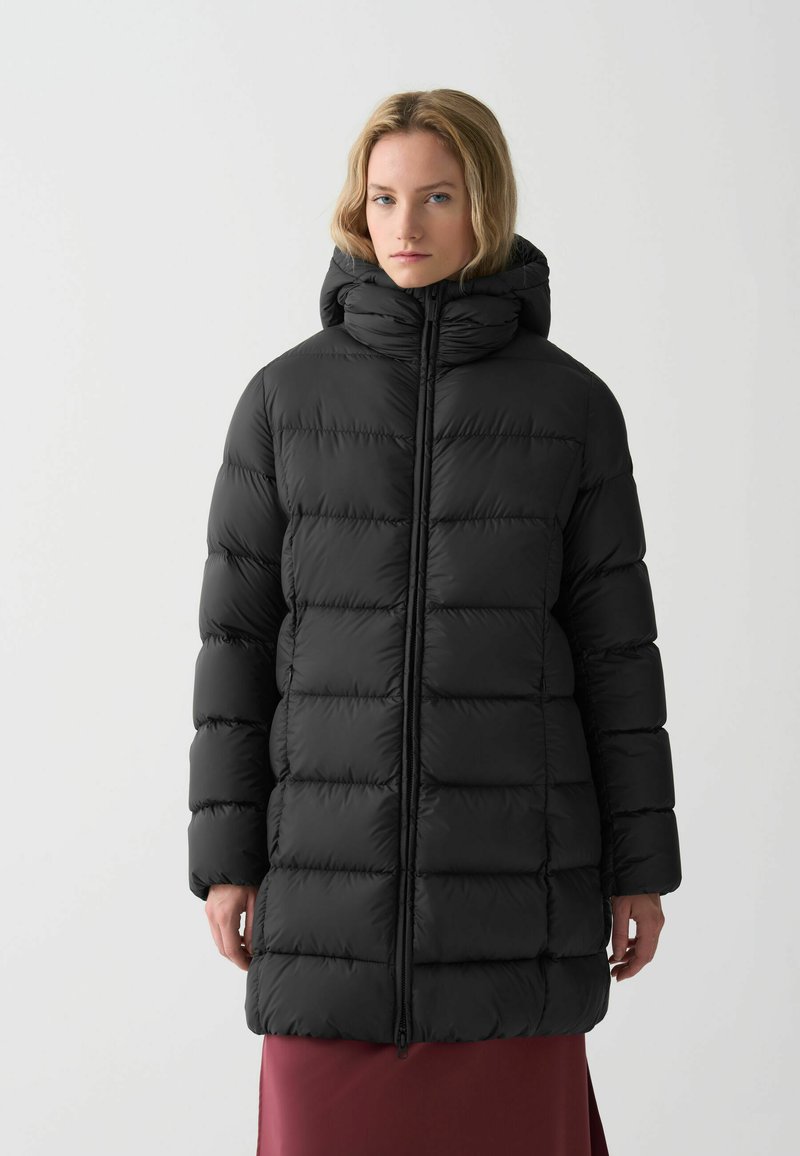 Melna pūkainā jaka ar augstu apkakli un kapuci, ar quilted sekcijām un priekšējo rāvējslēdzēju. Gluda, spīdīga tekstūra.