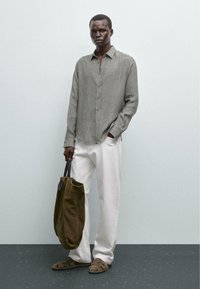 Light grey button-up shirt, white trousers, brown suede sandals, and an olive-green tote bag. Simple design with a casual look.
