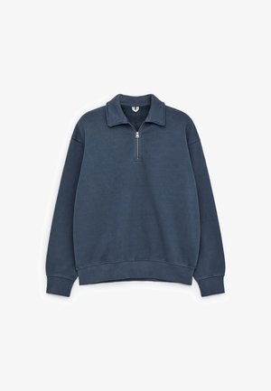 Granatowy sweatshirt z zamkiem błyskawicznym przy kołnierzyku, ściągaczami przy mankietach i u dołu, o miękkiej fakturze i luźnym kroju.