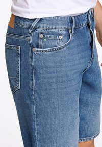 Lichtblauwe denim shorts met een klassieke snit, voorzien van een vijfzakkenontwerp en een bruine leren patch op de tailleband.