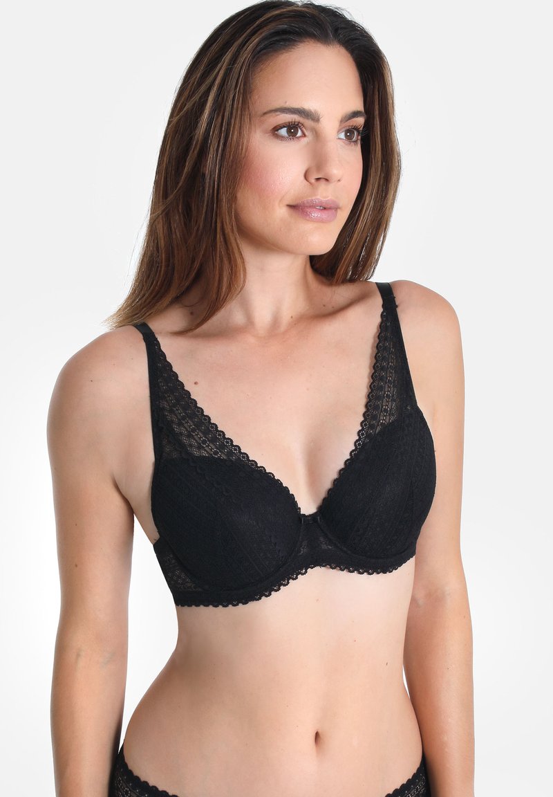 Schwarzer Spitzen-BH mit tiefem Ausschnitt, gewelltem Rand und verstellbaren Trägern. Strukturiertes Muster auf den Cups und ein zentrales Schleifendetail.