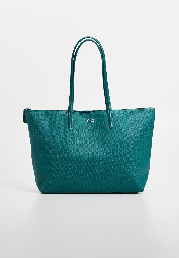 Bolso tote en color verde azulado con acabado texturizado, cierre de cremallera y dos asas largas. Presenta un pequeño logotipo en la parte frontal. Forma rectangular.