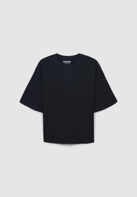 T-shirt nera tagliata con maniche corte, scollatura rotonda, realizzata in tessuto liscia. Presenta un'etichetta sul collo con la parola "CROPPED."