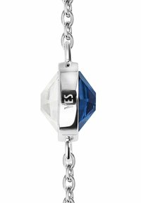 Bransoletka w srebrnym kolorze z dwoma fasetowanymi kamieniami szlachetnymi, jednym przezroczystym i jednym głęboko niebieskim, na ogniwowym łańcuszku, z wygrawerowanym napisem "TAK" na metalowej powierzchni.