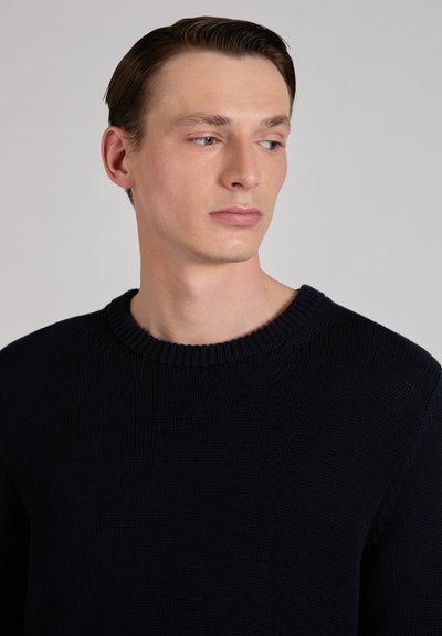 Suéter de punto azul marino con cuello redondo acanalado. La tela tiene un aspecto texturizado y el ajuste es holgado, adecuado para un uso informal.