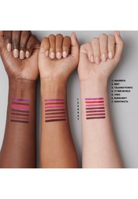 Trois bras montrent différents échantillons de couleurs de lèvres sur des teintes de peau : riche sombre, bronzage moyen et claire. Les échantillons affichent des teintes vibrantes allant du magenta au bordeaux.