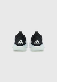 Chaussures de sport en noir et blanc avec une tige en mesh, un col rembourré et trois rayures blanches sur le talon. Semelle en caoutchouc transparent.