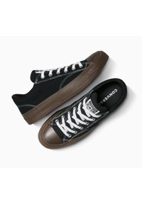 Sneakers neri in tela con lacci bianchi, punte in gomma e suole in gomma marrone. Caratterizzati da cuciture classiche e logo sulla linguetta.