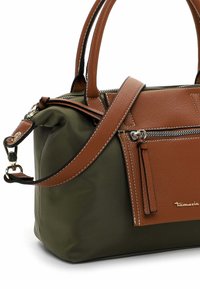 Sac à main vert et marron avec deux poignées, poche zippée à l'avant et bandoulière amovible, agrémenté d'accents en cuir texturé et de ferrures métalliques.