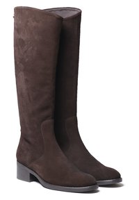 Bottes en daim marron jusqu'au genou avec un embout légèrement arrondi et un petit talon carré. Présente des détails de couture discrets sur les côtés.