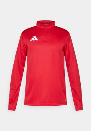 Czerwona sportowa koszulka z długim rękawem i golfem na zamek ćwiartkowy, wykonana z lekkiego materiału, z białym logo Adidas na lewej piersi.