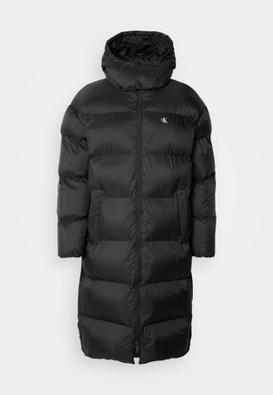 Melna pūkainā jaka ar kapuci, ar izšūtu dizainu, priekšējo rāvējslēdzēju un divām priekšējām kabatām. Materiāls izskatās gluds un spīdīgs.