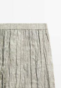 Jupe en mélange de coton avec une ceinture élastique, présentant des plis verticaux dans une couleur grise douce, une texture lisse et un design léger.