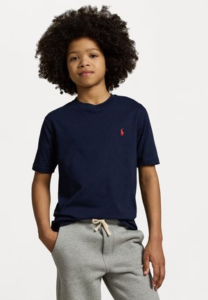 Navy blue cotton t-shirt with a crew neck and short sleeves, featuring a small red logo on the chest, paired with gray sweatpants.
