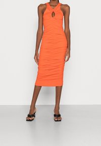 Oranžové žebrované midi šaty s výstřihem ve tvaru klíče, přiléhavého střihu, texturované tkaniny a detailem řasení, doplněné černými sandály na blokovém podpatku.