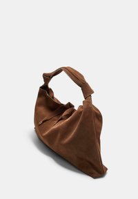 Brun suedetaske med en bred, struktureret form, der har en foldet top og et tykt håndtag. Glat tekstur med subtile syningsdetaljer.