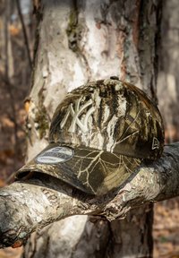 Gorra de béisbol de camuflaje con visera curva, que presenta un logotipo de Nueva York en relieve de color claro, hecha de tela con patrones de corteza de árbol.
