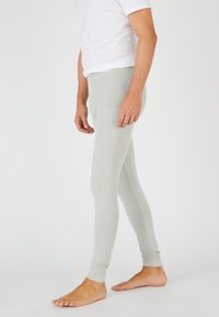 Leggings de algodón grises con un diseño ajustado, textura suave y dobladillos en los extremos, complementados con una camiseta blanca de manga corta.