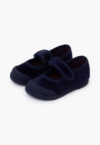 Zapatos de terciopelo azul marino con punta redondeada, suela de goma y correa ajustable en el empeine. Detalles texturizados en la punta y el tacón.