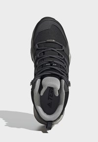 Mustamäki vaelluskengät, joissa on teksturoitu kangas päällinen, harmaa verkkokaulus ja kumipohja. Varustettu harmailla kengännauhoilla ja vahvistetulla kantapäällä tuen tarjoamiseksi.