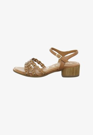 Brown leather sandal featuring an open-toe design, decorative cutouts, metallic accents, and a low block heel with a wood-like texture.