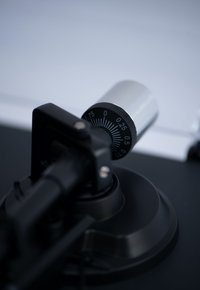 Black adjustable microphone stand with a silver control knob. The knob features a dial marked with numbers for precise adjustments.