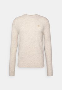 Pull en tricot beige avec un col rond, des manches longues et un petit logo doré sur la poitrine, fabriqué en tissu doux et texturé.