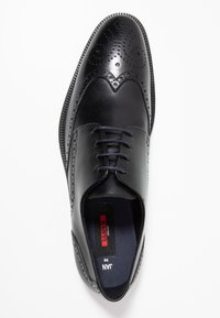 Chaussure habillée en cuir noir avec un bout arrondi, des détails de brogue délicats et cinq œillets de lacets. Texture lisse avec une semelle robuste.