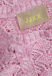 Megztinis rožinės spalvos su atviru siūlų raštu; turi béžinės spalvos etiketę su "JJXX" geltonai. Minkšta tekstūra, lengvas dizainas.