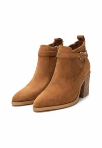 Botines de ante marrón con punta afilada y tacón cuadrado, con recortes decorativos y una correa con detalle de hebilla.