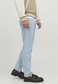 Ljusblå denimjeans, avslappnad passform, med en mjuk textur. Matchas med mörkbruna loafers med en dekorativ rosett.