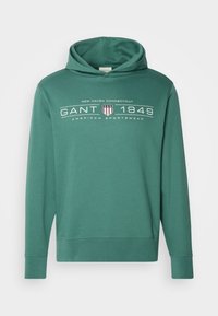 Felpa verde con tasca a marsupio, maniche lunghe e stampa del logo che recita "GANT 1949". Realizzata in materiale morbido e traspirante.