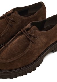 Braune Wildlederschuhe mit rundem Zehenbereich, Schnürdesign und strukturierter Gummisohle. Mit glattem Innenfutter und gesteppter Verarbeitung.