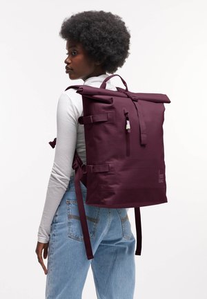 Purple roll-top backpack with adjustable straps, zip pocket, and logo. Made of durable material, featuring smooth texture and minimalistic design.
