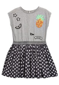 Robe grise à manches courtes avec un décolleté arrondi, ornée d'une broderie en forme d'ananas texturé, d'une jupe à motif floral noir et blanc, et de patchs décoratifs.