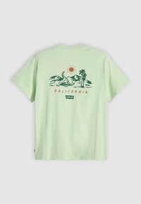 Svijetlozelena pamučna majica opuštenog kroja, s grafičkim dizajnom planina, sunca, palmi i natpisom "KALIFORNIJA" u crvenoj boji.