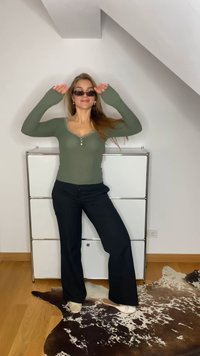Camisola de manga longa verde com riscas, decorada com renda e detalhes de botões, combinada com calças largas pretas e sapatos bez em slip-on.