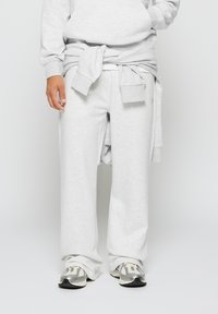Lyse grå, avslappede joggebukser i et mykt stoff med bred bendesign. Kombinert med grå joggesko for et avslappet utseende.