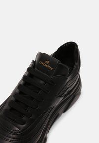 Svart lädersneaker med rund tå, texturerade detaljer och dämpad sula. Har platta snören och en etikett med "COPENHAGEN" i guld.