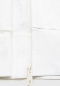 Tessuto di felpa bianco con sezioni testurizzate e lisce, dotato di una zip laterale di colore avorio. Design semplice senza motivi o accenti.