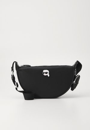 Borsa a spalla nera in nylon con forma curvilinea, caratterizzata da una chiusura con zip, una tracolla regolabile e un logo rialzato ben visibile sulla parte anteriore.