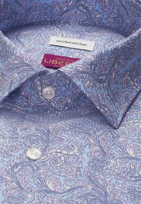 Chemise bleu clair avec un motif paisley violet complexe, boutons blancs et étiquettes indiquant "seidensticker" et "Made with Liberty Fabric."