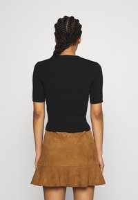 Black ribbed short-sleeve top paired with a brown suede flared skirt. The outfit features a fitted silhouette and textured materials.